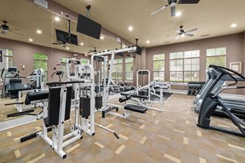 a gym with weights and cardio equipment and windows